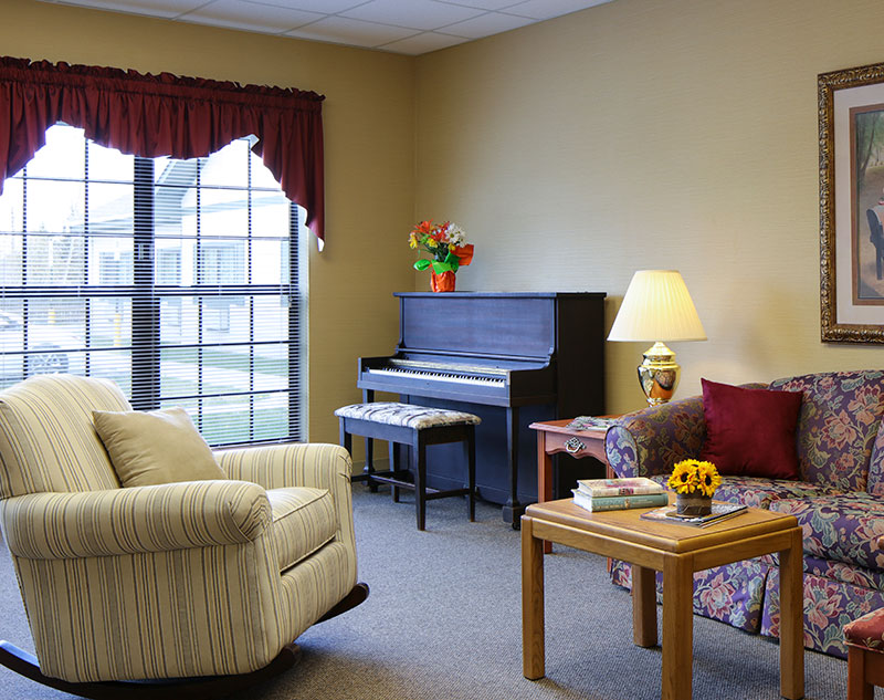 Lounge with comfy seating, recliner chair, and grand piano in Madison, Virginia nursing home.