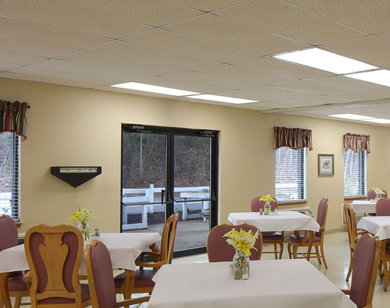Dining room with four person tables in Madison, Virginia nursing home.