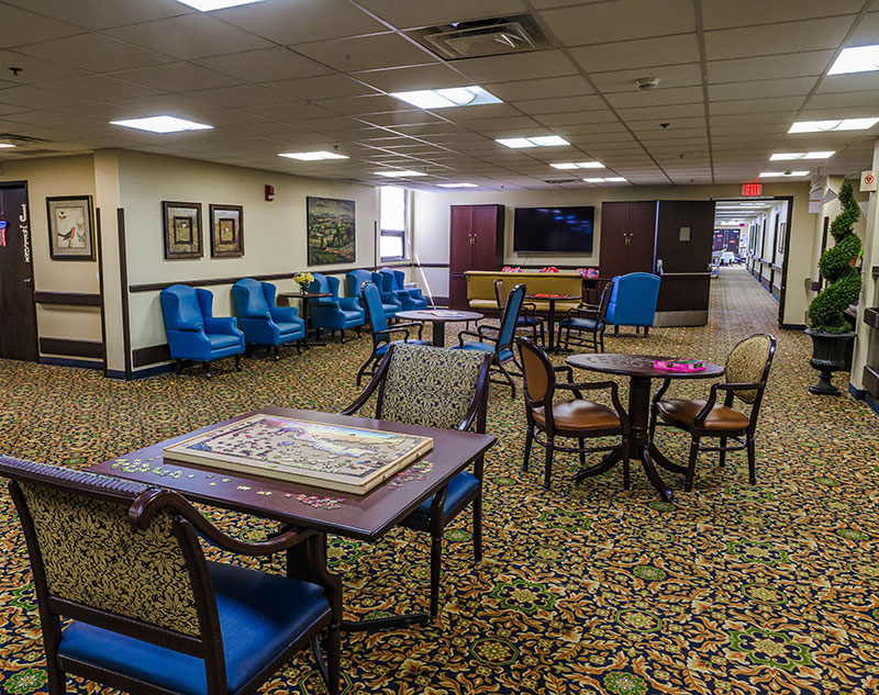 Activities room with puzzles, game tables, and flat-screen television in Ebensburg, Pennsylvania assisted living facility.